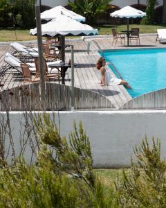 a woman is sitting in a swimming pool at Hotel Vale Da Telha in Aljezur