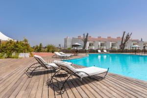 a deck with lounge chairs and a swimming pool at Hotel Vale Da Telha in Aljezur