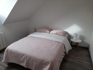 a white bedroom with a bed with pink pillows at Appartement moderne et spacieux in Sedan +7 photos