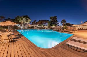 a swimming pool at night with chairs and umbrellas at Hotel Vale Da Telha in Aljezur