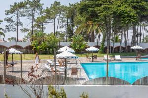 a woman walking next to a swimming pool at Hotel Vale Da Telha in Aljezur