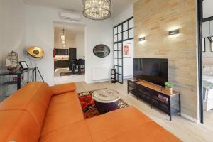 sala de estar con sofá naranja y TV en Synagoge view loft bestern, en Szeged