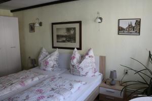 um quarto com uma cama com almofadas cor-de-rosa e brancas em Pension Zum Lukullus em Wernigerode