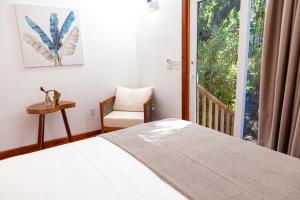 ein Schlafzimmer mit einem Bett, einem Stuhl und einem Fenster in der Unterkunft Angeli Gardens Boutique Hotel in San Pedro Sula
