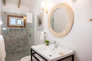 a white bathroom with a sink and a mirror at Angeli Gardens Boutique Hotel in San Pedro Sula