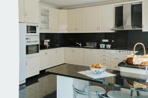 a kitchen with white cabinets and a bowl of fruit on a counter at Regina Beach - Villa with Private Pool in Viana do Castelo