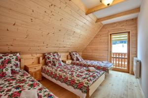 a log cabin bedroom with two beds and a window at Domki Stochowa Śleboda in Bukowina Tatrzańska