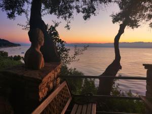 una estatua sentada en una pared cerca del agua al atardecer en ArokariApartments, en Koroni