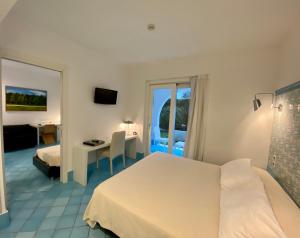 a hotel room with a white bed and a desk at Ganimede Hotel in Sperlonga