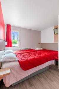 a large red bed in a bedroom with a window at Premiere Classe Rennes Ouest - Le Rheu in Le Rheu