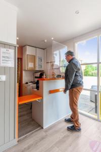 a man standing at a counter in a kitchen at Premiere Classe Rennes Ouest - Le Rheu in Le Rheu