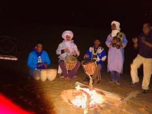 Eine Gruppe von Menschen, die um ein Feuer herum sitzen in der Unterkunft Riad Hotel Les Flamants in Merzouga