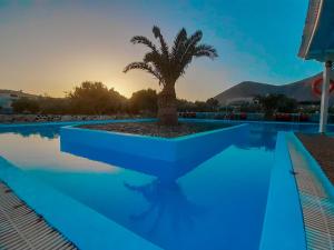 a swimming pool with a palm tree in the middle at The Three anchors Rooms Perissa in Perissa