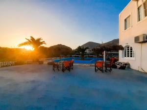 a patio with chairs and a swimming pool at sunset at The Three anchors Rooms Perissa in Perissa