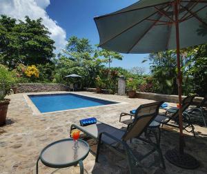 um pátio com cadeiras, um guarda-sol e uma piscina em Architectural home, Pool and High Speed Internet em Puntarenas