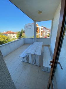 una panca di legno su un balcone con tavolo di Апартамент "Вила Аква" a Burgas