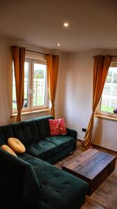 a living room with a green couch and two windows at Ośrodek Wypoczynkowo Sportowy Pod Żurawiem Apt. 2 in Karolewo