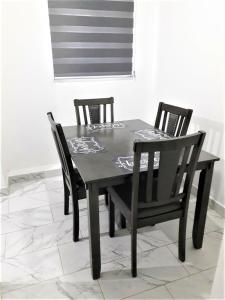 una mesa de comedor negra con 2 sillas y una ventana en Santa Fé Apartamentos en Puerto Peñasco