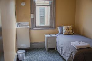 a small bedroom with a bed and a window at Hotel Cessnock in Cessnock