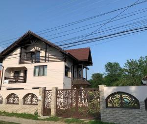 una casa bianca con una recinzione e un cancello di Pensiunea Valea Șușiței, Ciubar, Sauna, ATV, Safarii Jepp Offroad Ghid Turistic, Climbing, Rafting, Paragliding a Târgu Jiu