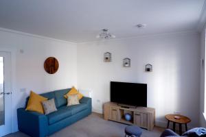 a living room with a blue couch and a flat screen tv at No 7 Quiet, two bedroom Ground Floor Flat in Tornagrain Great for early Airport departures or late flights in Dalcross