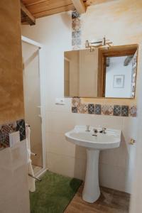 a bathroom with a white sink and a mirror at Casa de la Era, grande, de adobe, con patio y bodega in Fontanil de los Oteros