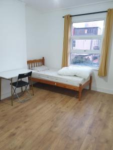 uma cama num quarto com uma janela e uma secretária em Burney Tomar House em Croydon