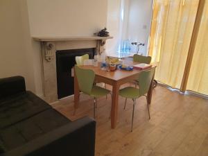 uma mesa e cadeiras numa sala de estar com lareira em Burney Tomar House em Croydon