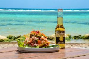a plate of salad and a bottle of beer on the beach at Eco Cabañas Bluekay in Mahahual