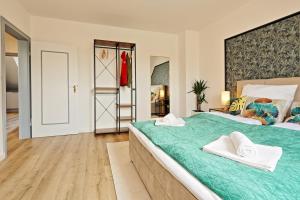 um quarto com uma grande cama verde e 2 toalhas brancas em NEAR MESSE! - Stay&Dream - 50qm - City - Kitchen - Netflix em Krefeld