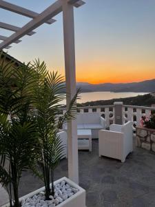 eine Terrasse mit weißen Möbeln, Palmen und Sonnenuntergang in der Unterkunft SUNSET SUITE in Capoliveri