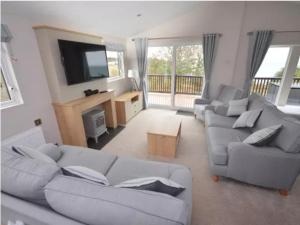 a living room with couches and a flat screen tv at Coastal View in Brixham
