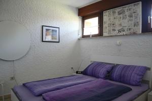 - une chambre avec un lit doté de draps violets et une fenêtre dans l'établissement Appartment 2107 in Tossens, à Tossenserdeich