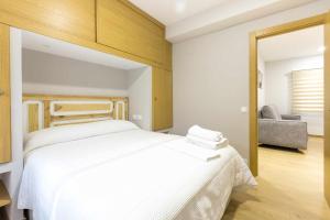 um quarto com uma grande cama branca e uma cadeira em Las tres puertas em Zamora