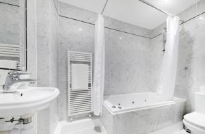 uma casa de banho com um lavatório, uma banheira e um WC. em Stunning Kensington apartment em Londres