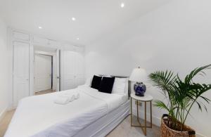 a white bedroom with a white bed and a table at Stunning Kensington apartment in London