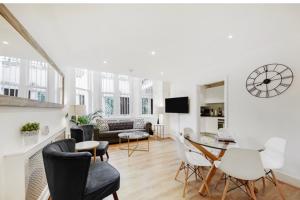 ein Wohnzimmer mit einem Sofa, einem Tisch und Stühlen in der Unterkunft Stunning Kensington apartment in London