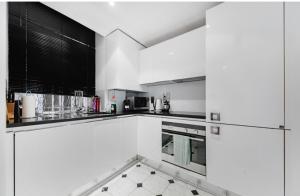a white kitchen with black and white appliances at Stunning Kensington apartment in London