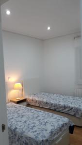 ein Schlafzimmer mit 2 Betten und einem Tisch mit einer Lampe in der Unterkunft Amplio piso exterior en el centro de Santander in Santander