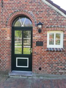 an entrance to a brick building with a black door at Ferienwohnung Rendelchen in Großheide