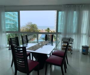 une salle à manger avec une table, des chaises et une grande fenêtre dans l'établissement Morros 3 - Vista y salida directa al mar, à Carthagène des Indes
