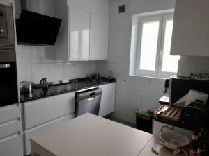 małą kuchnię z białymi urządzeniami i oknem w obiekcie Amplio piso exterior en el centro de Santander w mieście Santander +7 zdjęć