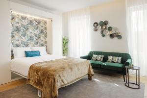 een slaapkamer met een bed en een groene bank bij The Downtown Charming Apartments in Porto