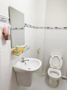 ein weißes Bad mit einem Waschbecken und einem WC in der Unterkunft Huy Hoàng Hotel in Ho-Chi-Minh-Stadt