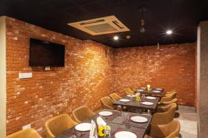 a dining room with tables and chairs and a brick wall at Treebo Fourth Avenue in Chennai