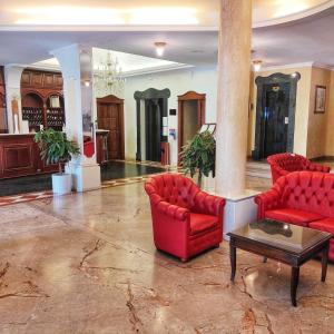 una hall con due sedie rosse e un tavolo di Mariano IV Palace Hotel a Oristano