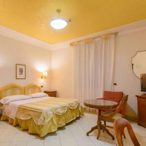 
a bedroom with a bed, chair and a lamp at Mariano IV Palace Hotel in Oristano
