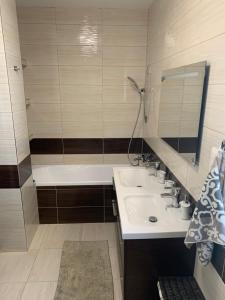 a bathroom with a sink and a tub and a mirror at Modern 2 bed house near Bratislava with parking in Rovinka