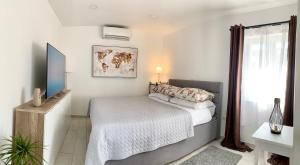 a white bedroom with a bed and a television at Apartment Ana Sea View in Makarska +16 photos