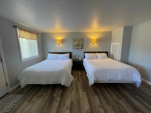 two beds in a room with wood floors at Misty Harbor Resort in Gilford